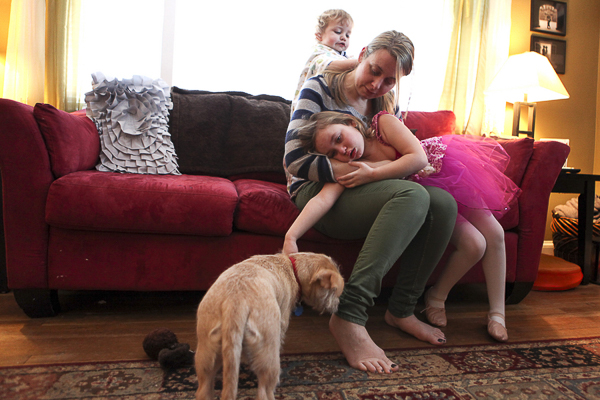 mom, daughter, toddler son on red sofa, puppy on floor