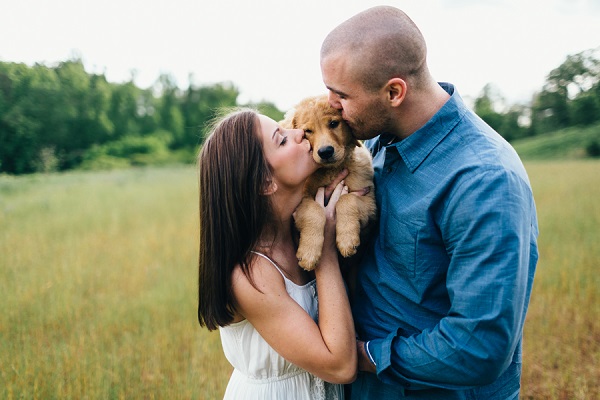 Erin Morrison Photography | couple kissing puppy while standing in a field