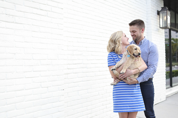 couple holding Golden Retriever puppy, white brick wall background