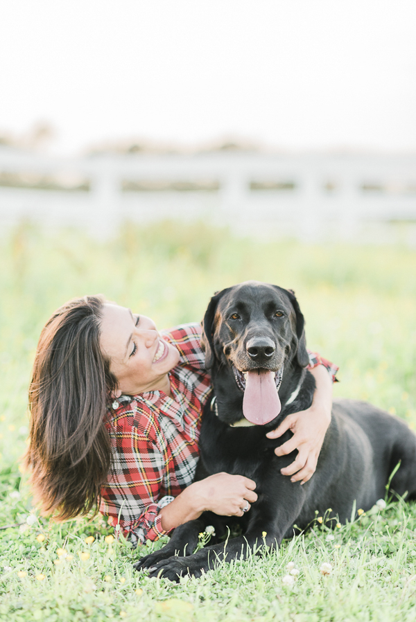 woman in plaid shirt and her black lab lying on the ground