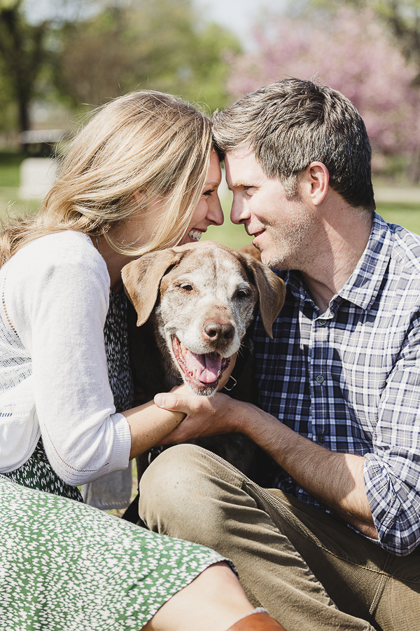 couple sitting down looking at each other with retriever between them
