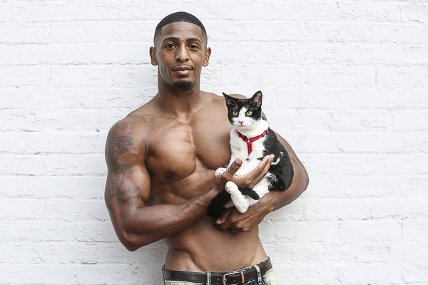 great looking guy holding black white cat, white brick background, fundraiser calendar for Norfolk SPCA