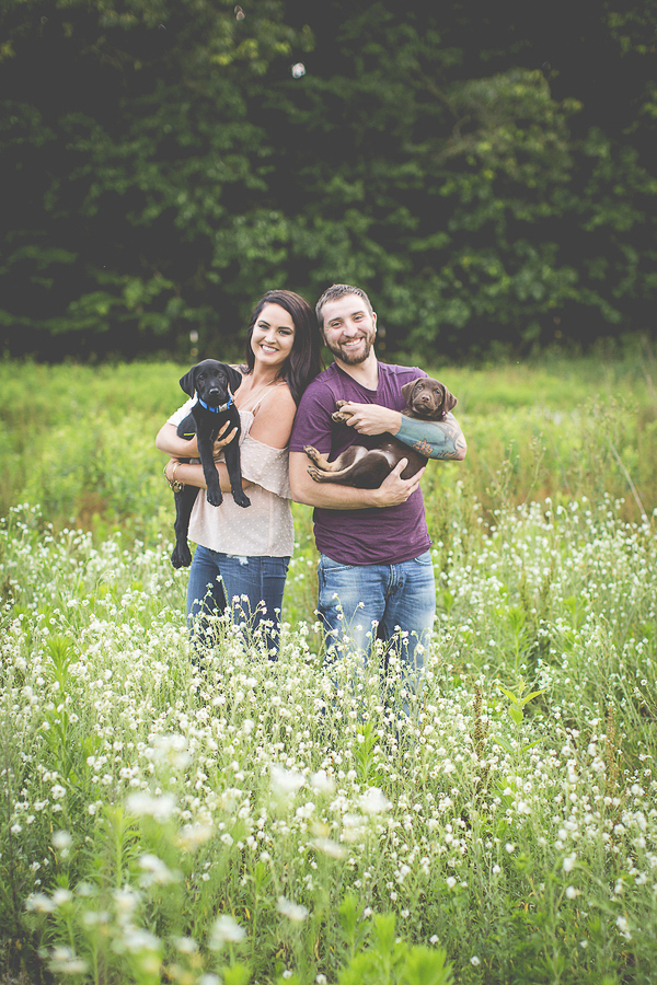 couple holding Lab pups in field, lifestyle dog photographer