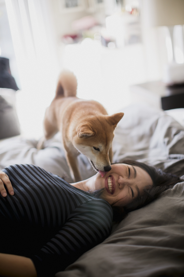 woman laughing as dog licks her, lifestyle pet photography