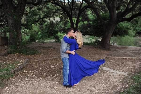 Austin TX engagement photos, woman in long flowing blue dress kissing man under big trees