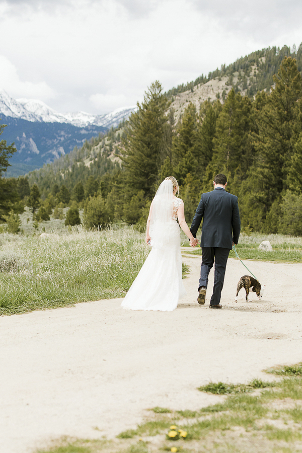 bride, groom and dog walking on dirt road in Rocky mountain setting, ©Elements of Light Photography