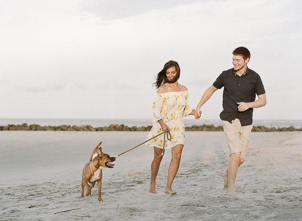 couple holding hands and running with their dog along the beach, ©Rachel Craig Photography |