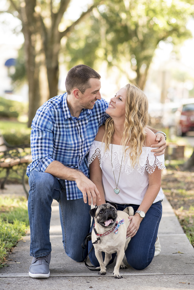 engaged couple kneeling on sidewalk with their Pug, ©Corner House Photography | Central Florida dog friendly engagement pictures