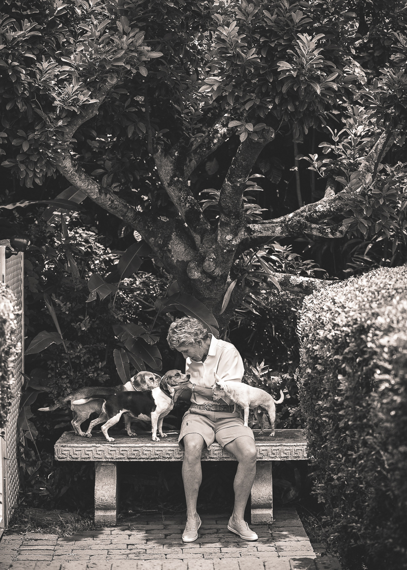 woman and her 3 dogs sitting on a bench in their yard | ©Amanda Emmes Photography, Oahu, Hawaii environmental dog portraits