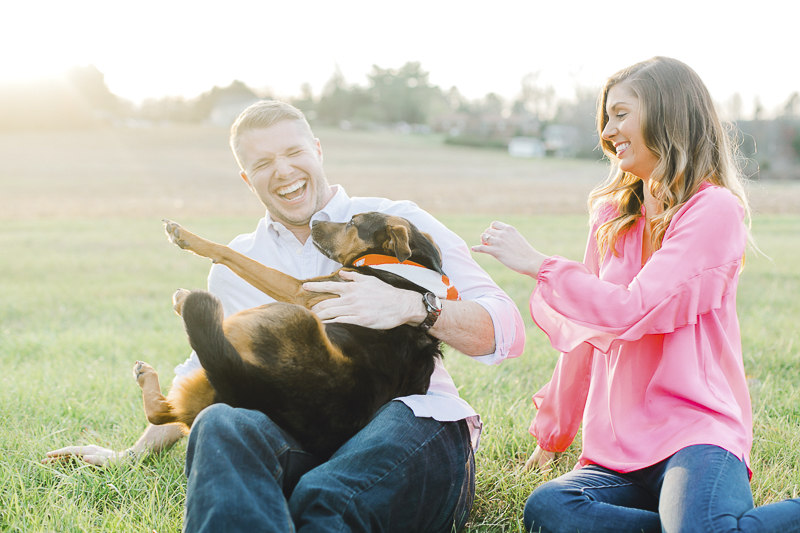 couple laughing with dog on man's lap, ©Casey Hendrickson Photography | Charlotte, NC Engagement photos with a dog