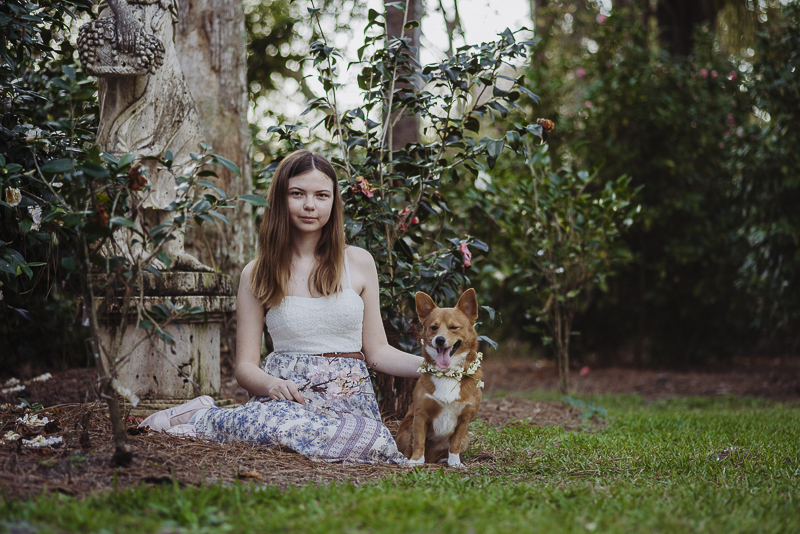 girl sitting on ground with Corgi in rose garden | ©DR Photography | Winter Park Portraits