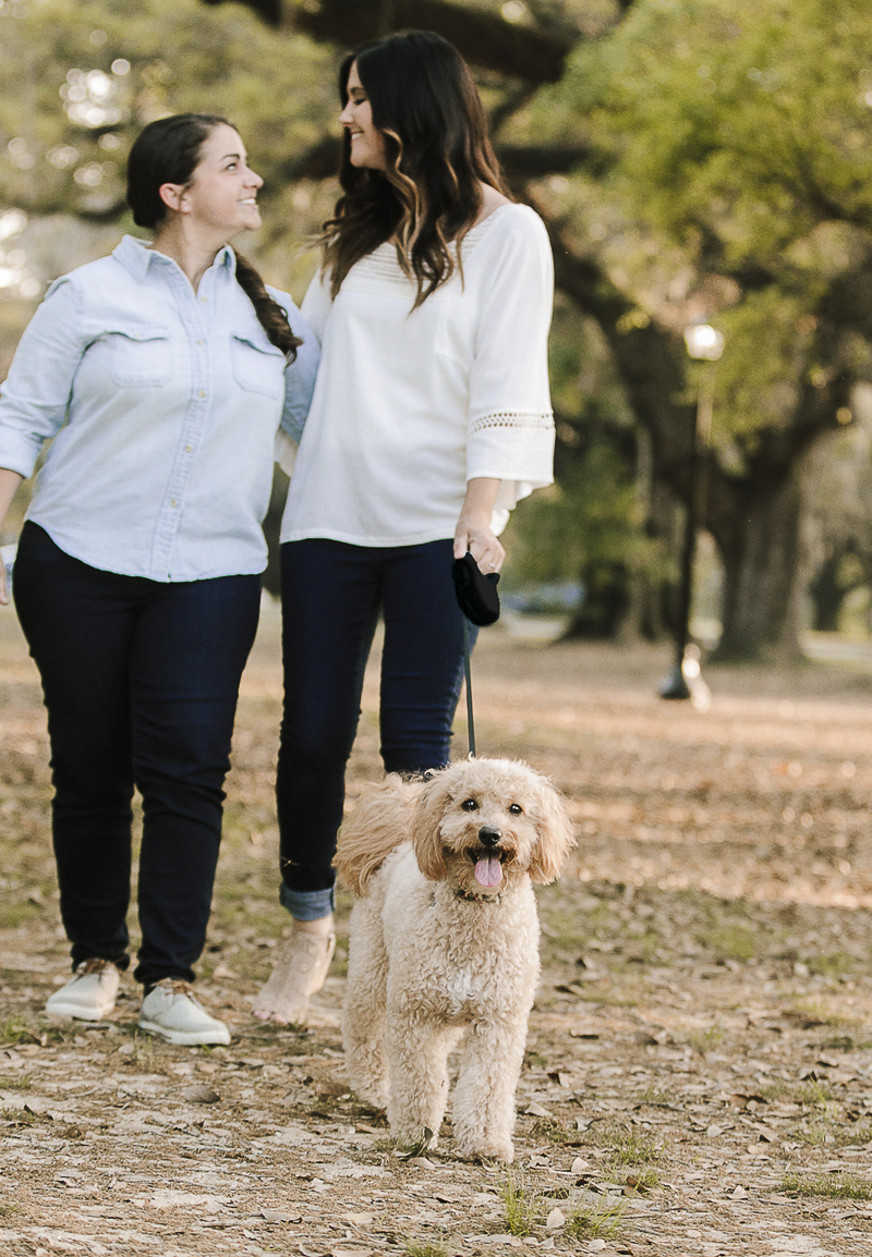 couple looking at each other while walking dog, ©Theresa Elizabeth Photography | same sex engagement photos, New Orleans, 