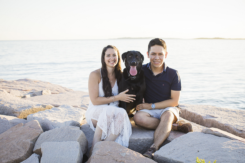 couple and Black Labrador Retriever sitting on rocks, beach engagement pictures, ©Trish Kemp Photography