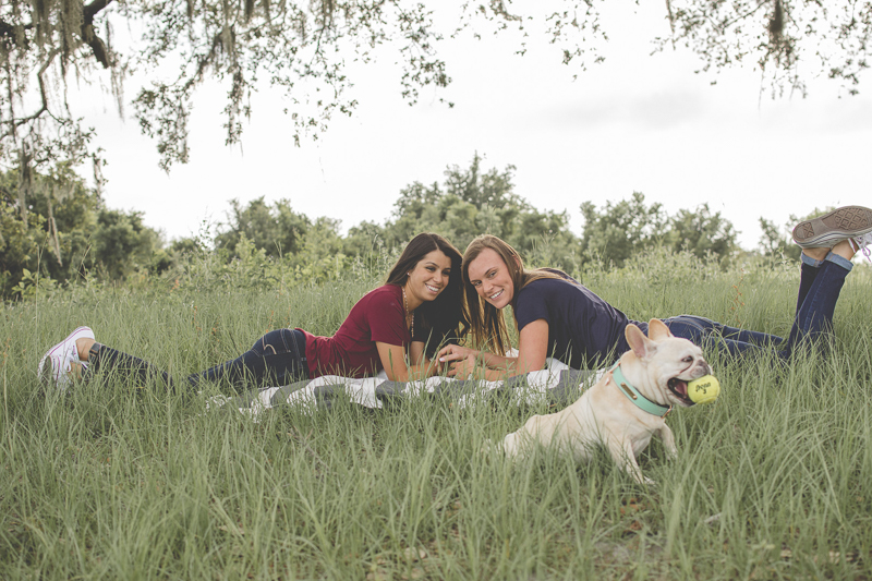 couple lying on blanket looking at Frenchie with tennis ball, ©Kimberly Santana Photography-dog-friendly summer engagement portrait session 