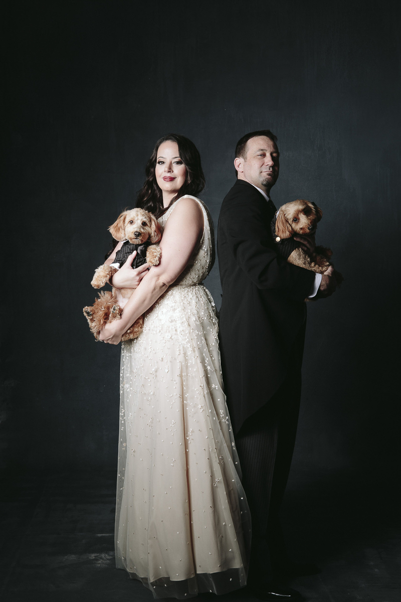 couple in formal wedding attire holding small brown dogs, ©Nicole Caldwell Photography | engagement photography with dogs, Orange, CA