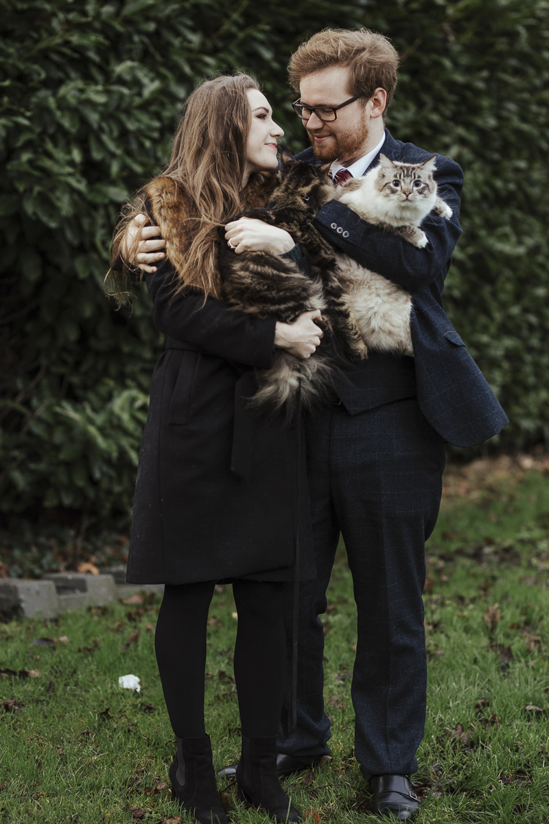 couple looking at each other while holding their cats, Ragdoll cat looking at photographer | ©Olga Hogan Photography 