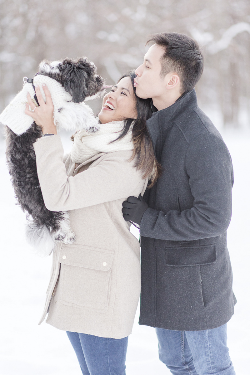woman holding dog up during winter engagement portraits, couple looking at their Shih Tzu mix, winter engagement session | ©Rebecca Sigety Photography