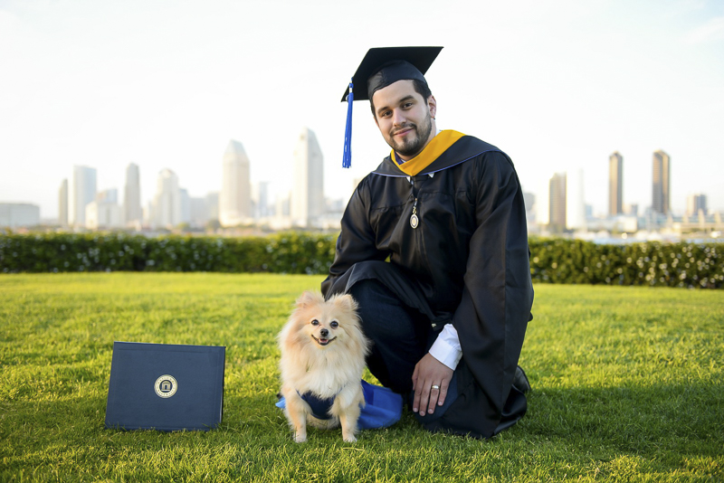 Graduation photos with a dog, man wearing cap and gown next to Pomeranian and diploma, Coronado, CA