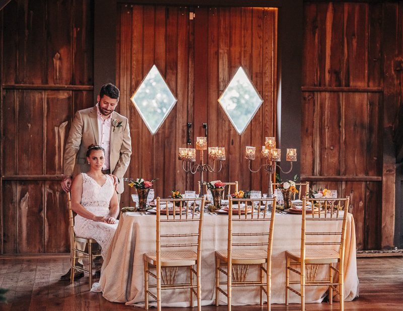Barn at Bohemia Outlook decorated for a wedding reception, bride and groom sitting at table, Landrum Photography