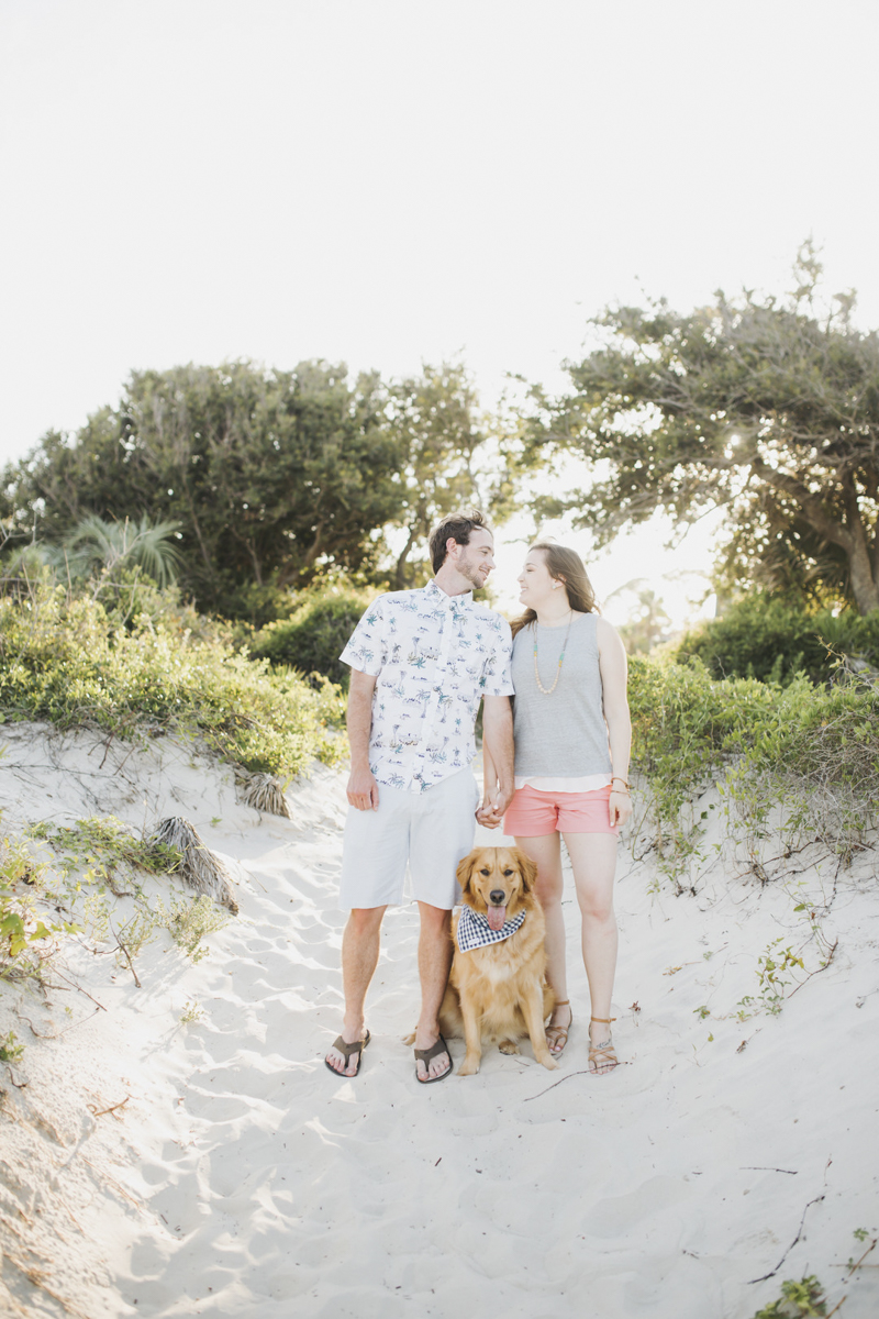 engaged couple and their dog in the sand, ©Rainey Gregg Photography | St. Simons Island, Georgia
