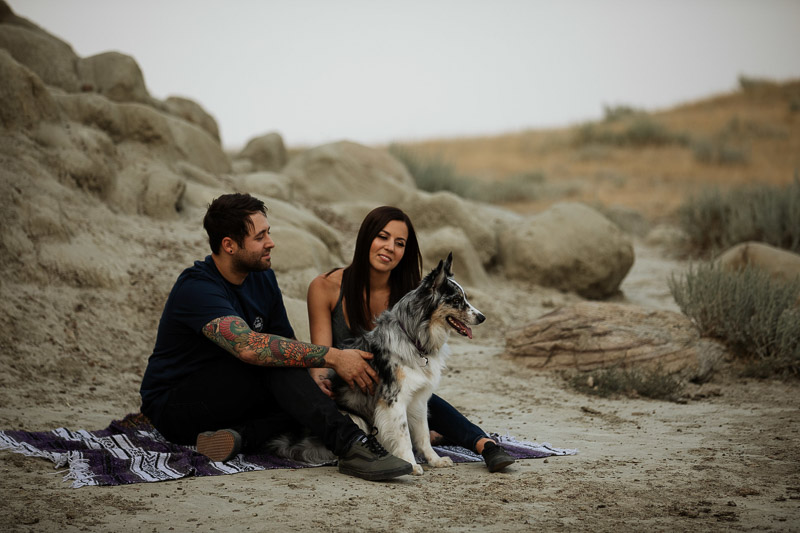 couple and their Aussie mix dog sitting on a blanket, dog-friendly engagement inspiration, ©Jackie Hall Photography | dog-friendly engagement portraits, Big Muddy Valley, SK, Canada