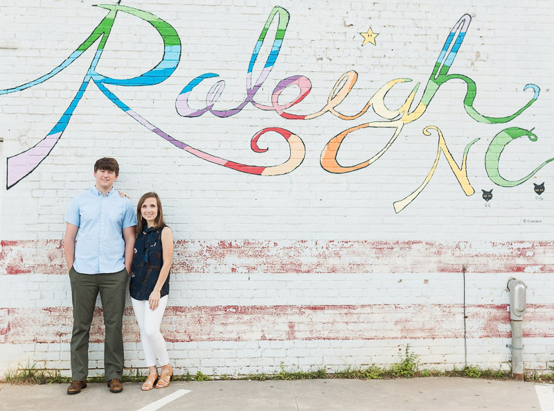 couple standing in front of Raleigh, NC mural, engagement session