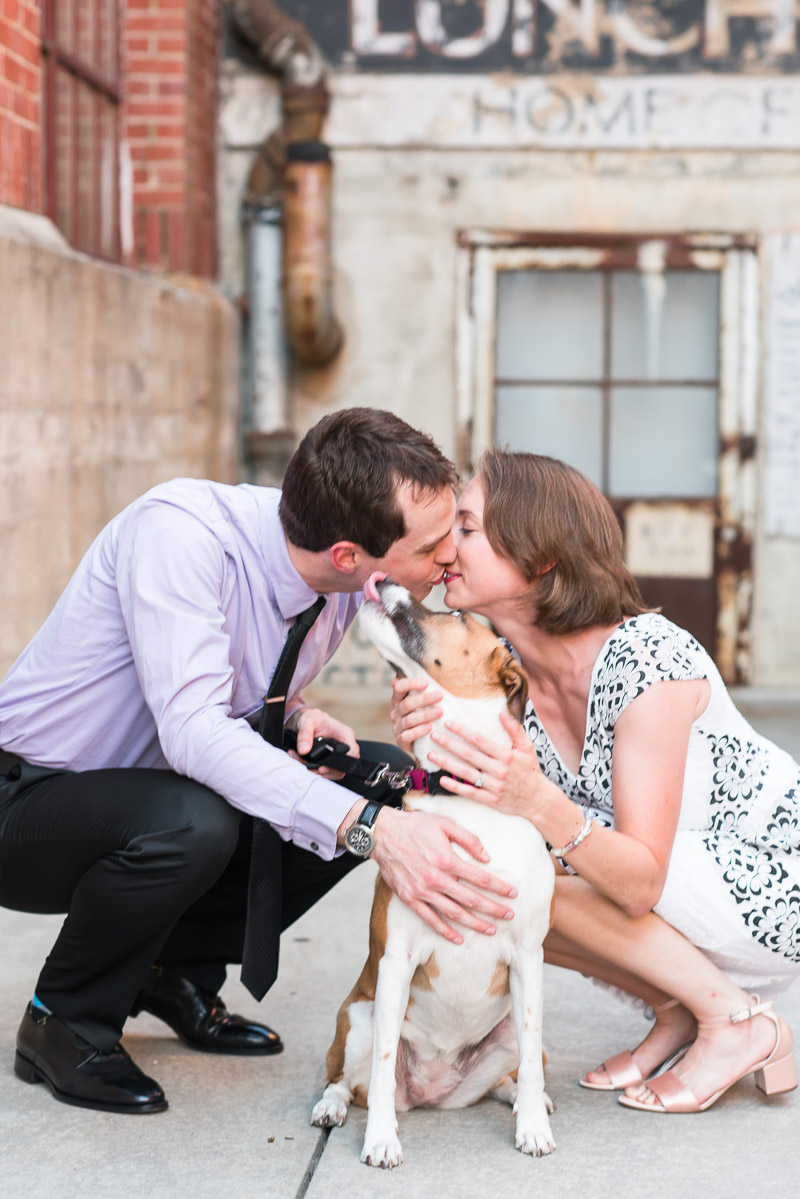 collie mix licking man's face while he kisses his fiancee, © Michelle and Sara Photography | American Tobacco Campus dog-friendly engagement photos