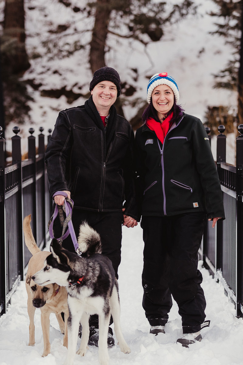 couple holding hands while walking dogs in the snow, dog photography ideas | ©Good Morrow Photography