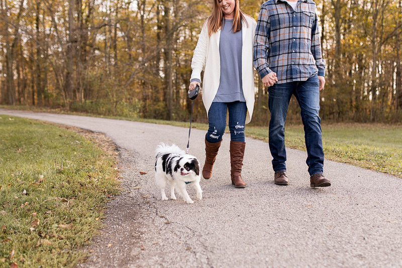couple holding hands and walking their small dog, ©Autumn Howell Photography | dog-friendly engagement session, Kokomo, Indiana