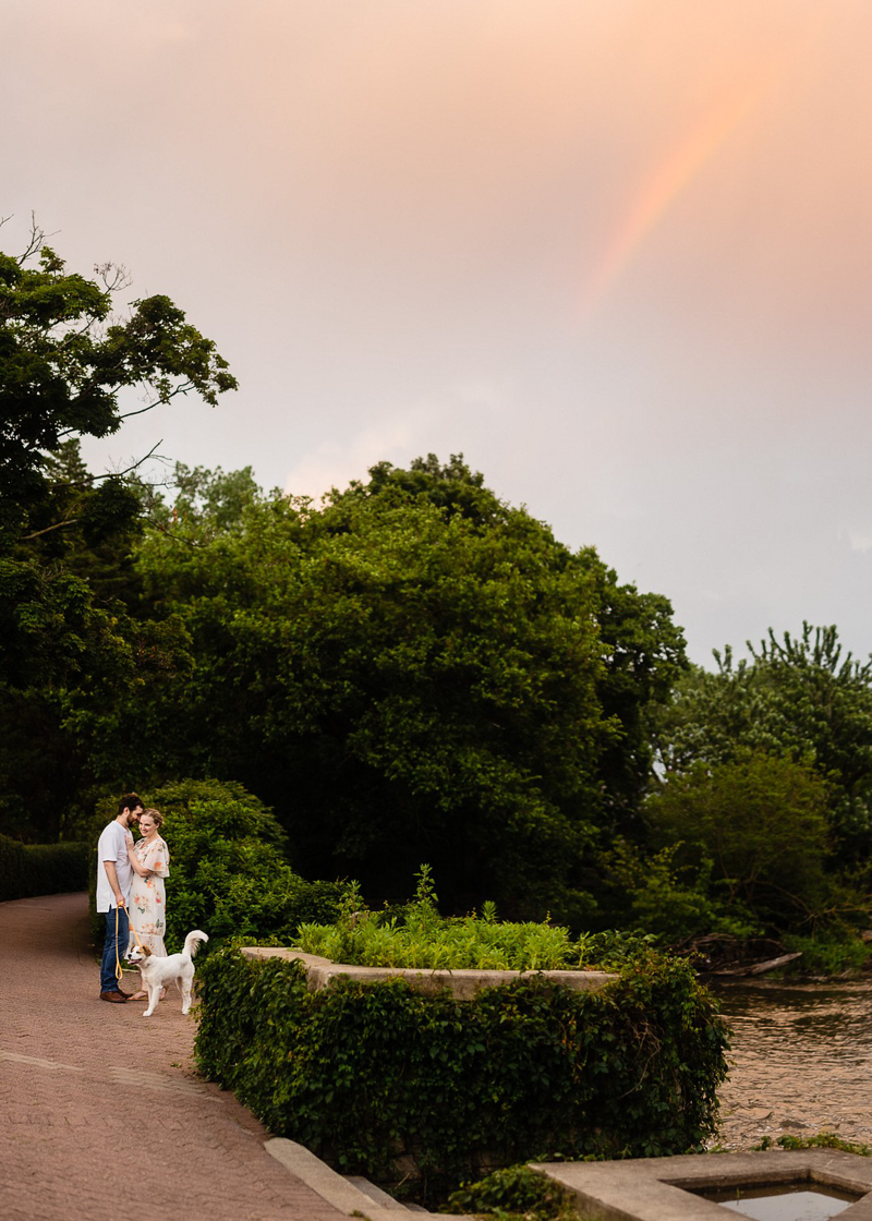 couple an d pup on brick path by river, rainbow, golden hour engagement session | ©Jennifer Lourie, Naperville, Illinois
