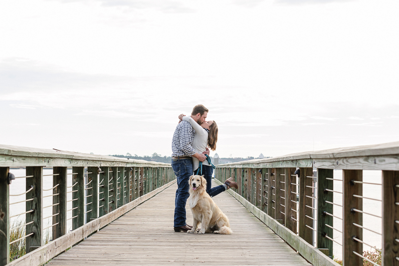 couple kissing on pier while dog sits in front of them | ©Charleston Photo Art, LLC, | 