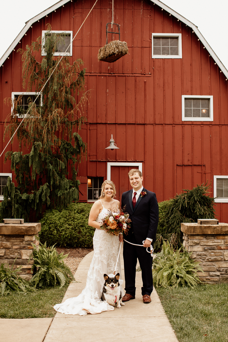 bride and groom with their Corgi in front of red barn, © McKenzie Bigliazzi Photography, Wright City, MO