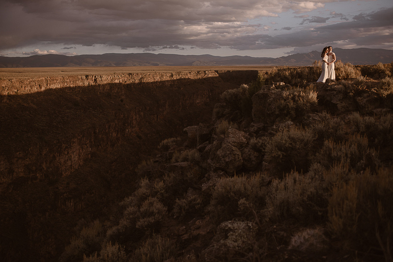two brides watching sunset at Rio Grande Gorge, NM | ©Adventure Instead Elopement Photography