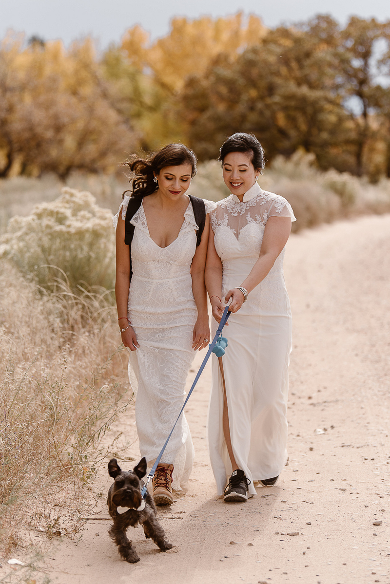 brides walking their dog on a trail, © Adventure Instead dog-friendly elopement photography, Abiquiú NM