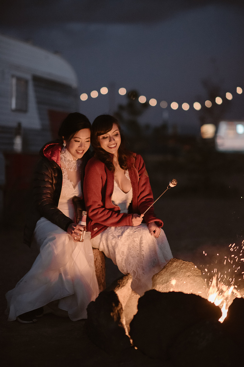 brides roasting marshmallow around a fire, ©Adventure Instead Elopement Photography, Taos, NM