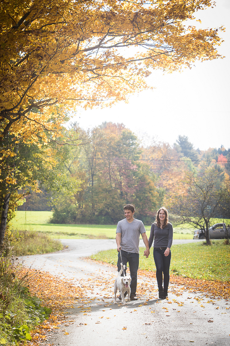 couple walking their dog while holding hands, Vermont fall engagement session, ©Cat Cutillo Photography