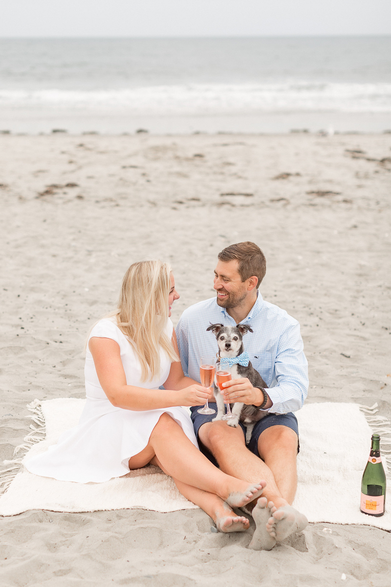 couple sitting on a blanket at the beach with their dog and champagne | ©Coli Michael Photography 