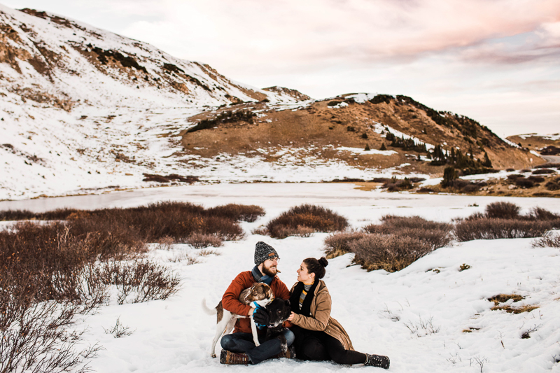 couple sitting in snow with Jack Russell/Aussie shepherd mix, adventure photography 