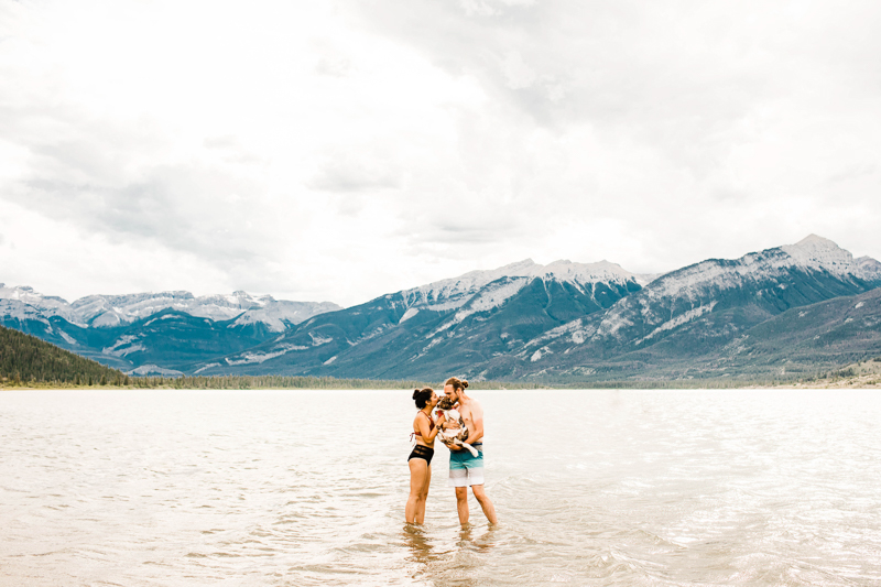 couple and their dog in gorgeous lake, mountains in background | ©Sheena Shahangian Photography | Adventure Elopement Photography