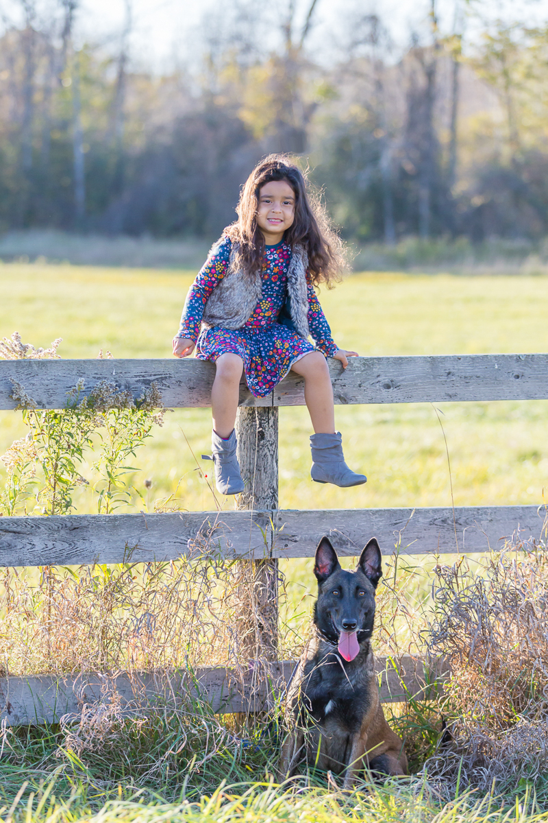young girl sitting on fence with Malinois sitting below her, kids and dogs portrait ideas, ©Terri J Photography
