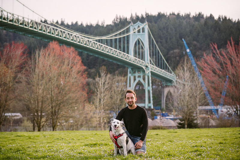man kneeling next to Border Collie mix puppy with bridge in background, Cathedral Park | ©Kelly Carmody Photography