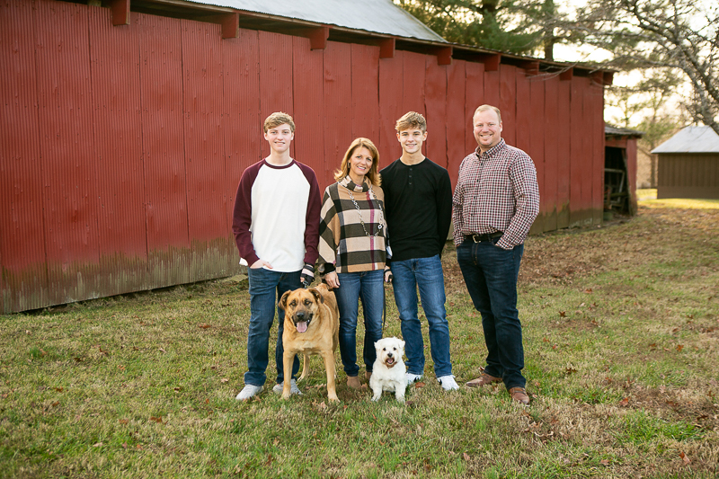 couple, teens, and dogs standing in front of red barn, dog-friendly family portraits | ©Mandy Whitley Photography