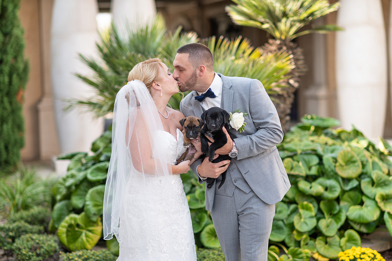 bride and groom kissing and holding rescue puppies | ©Ryan Smith Photography