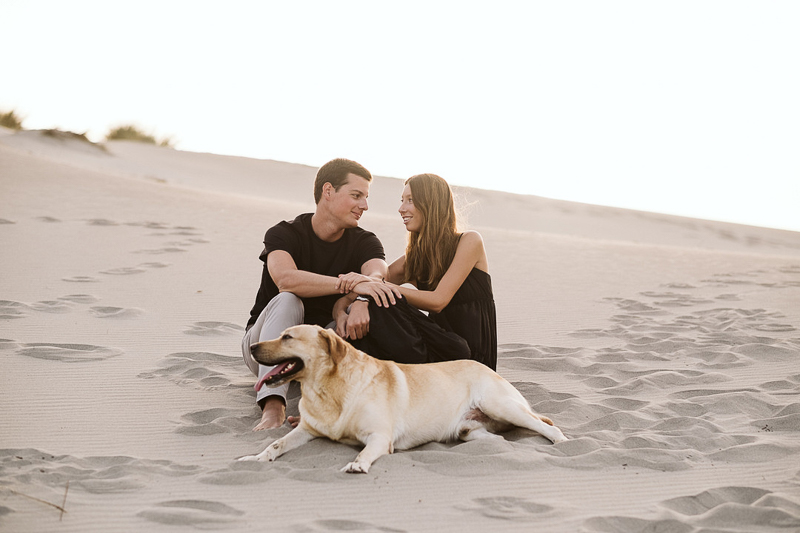 couple sitting on dunes, Yellow Lab in front of them | ©Blancorazon Weddings