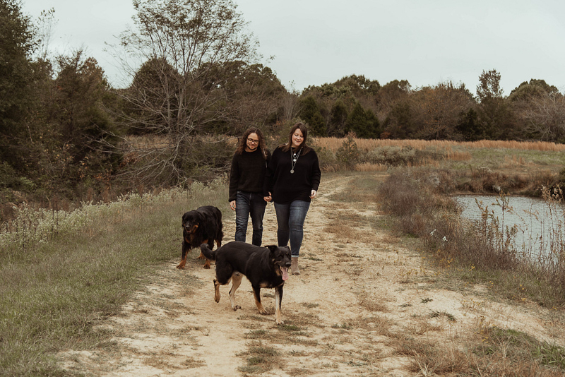 couple walking with their dogs on dirt path, dog-friendly engagement session, Memphis, TN | ©Emily Swan Photography 