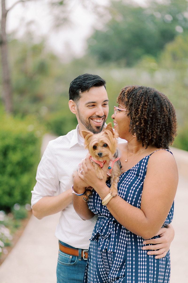 happy couple looking at each other while holding Yorkie | dog-friendly engagement,| ©Terrie Images