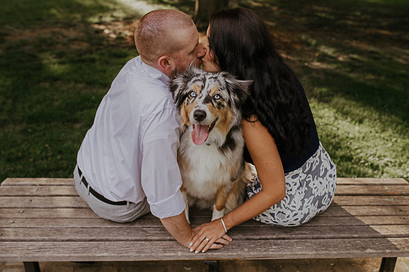 couple sitting on the bench with dog between them, dog-friendly engagement ideas | ©CityLux Studios