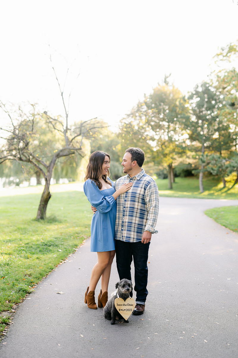 dog-friendly engagement photos, small dog wearing wood Save the Date, couple behind him | ©LaFountain Photography