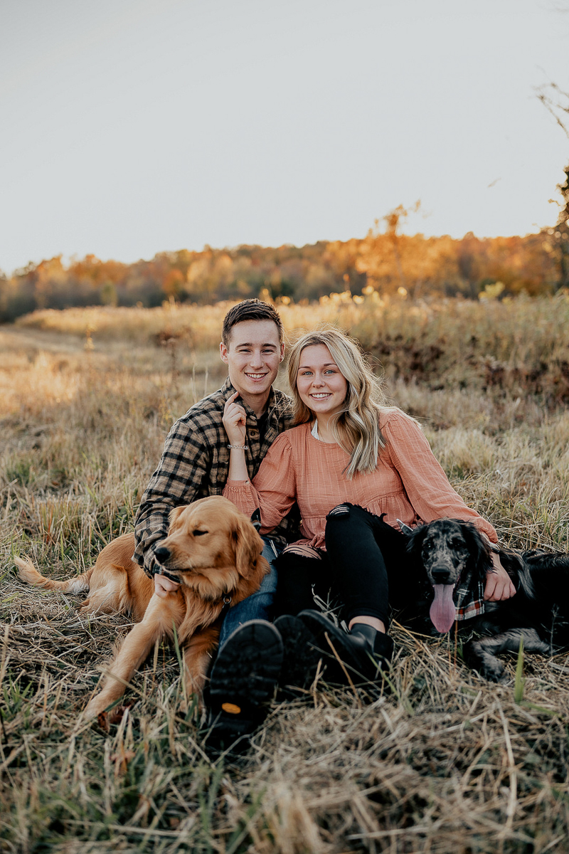 couple and their dogs sitting in a field, dog-friendly engagement photos ©Mindy Hulett Photography | CNY engagement and wedding photographer