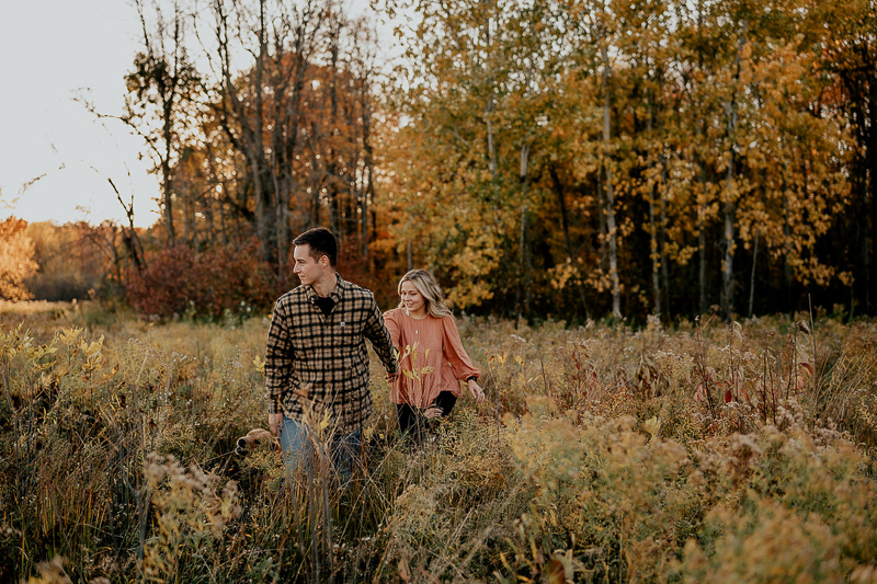 Fall engagement session, Central New York, couple holding hands walking through field